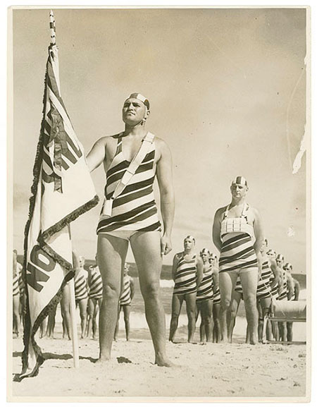 1935 sepia photo of North Bondi beach males in striped, full-body bathing costumes complete with bathing caps